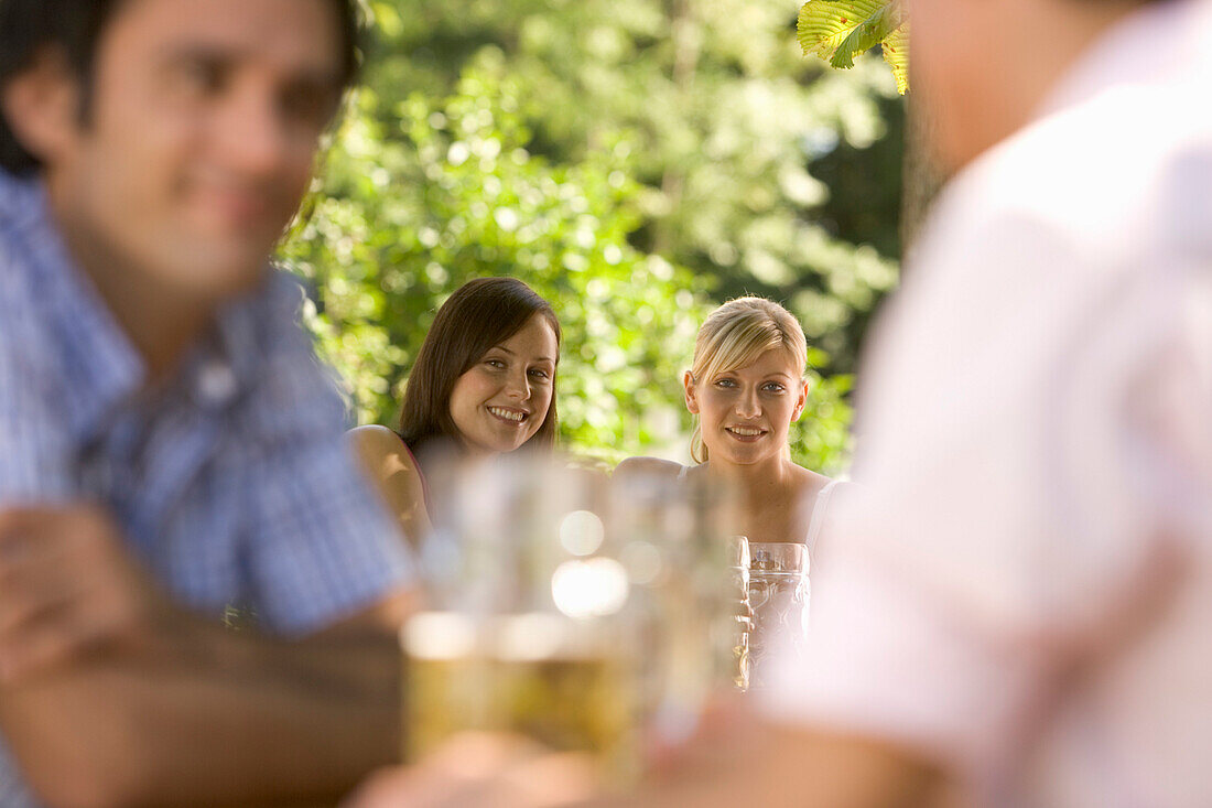 Young people smiling at each other in beer garden, Munich, Bavaria