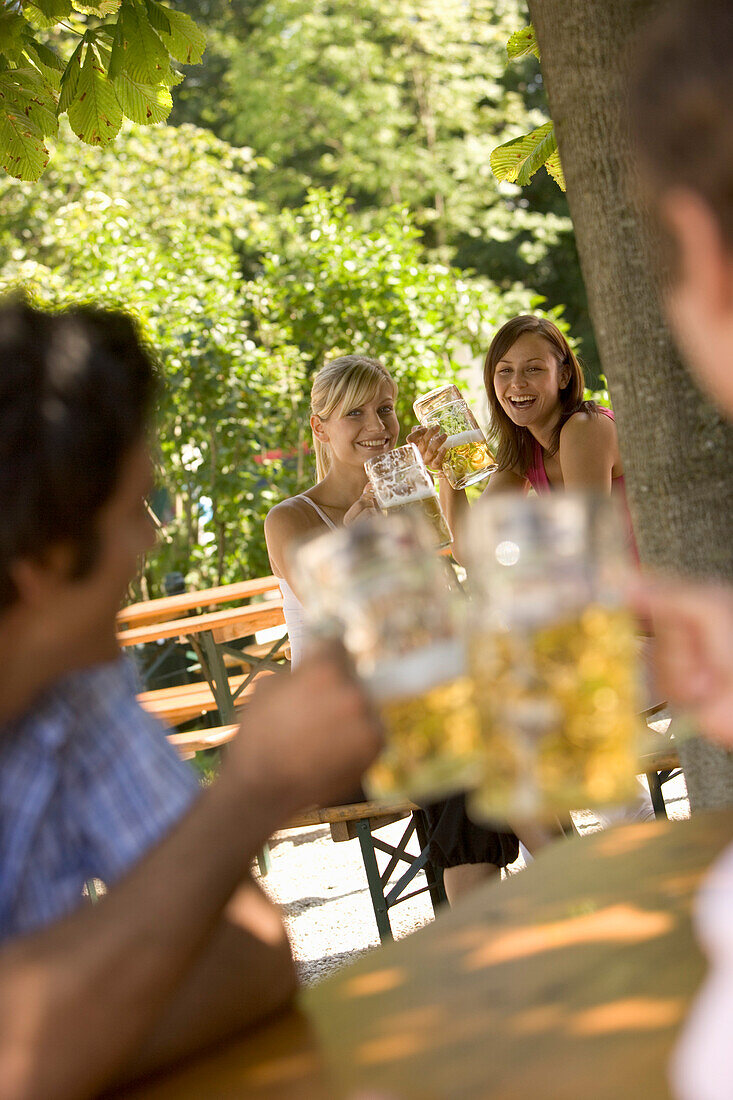 Flirt in Biergarten, Zwei junge Frauen und zwei Männer beim Flirten in Biergarten, Starnberger See, Bayern, Deutschland