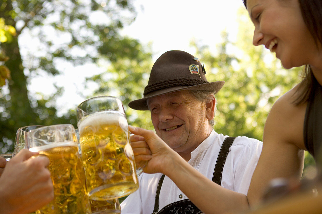 Older Bavarian man and young woman toasting each other, Munich, Bavaria