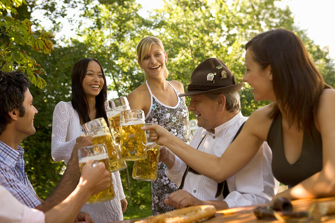 Cheerful people toasting each other in beer garden, Munich, Bavaria