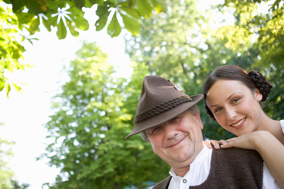 Older Bavarian man and young woman against trees, Munich, Bavaria