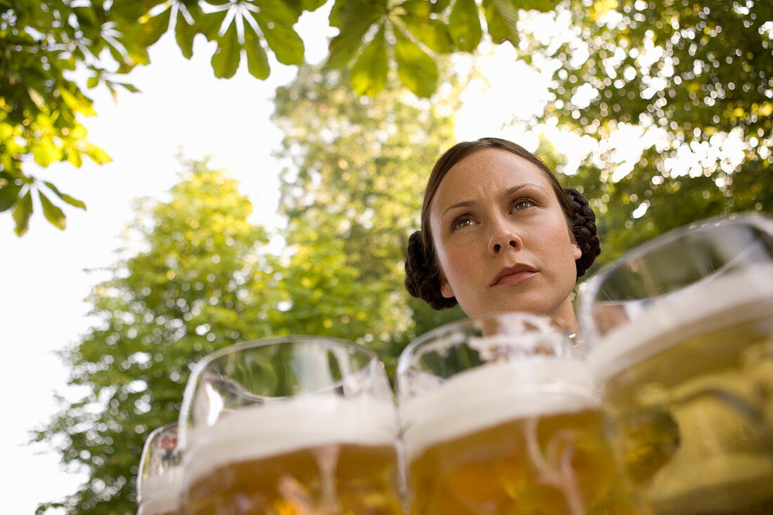 Bedienung mit Maßkrügen in Biergarten beim Starnberger See, Bayern, Deutschland