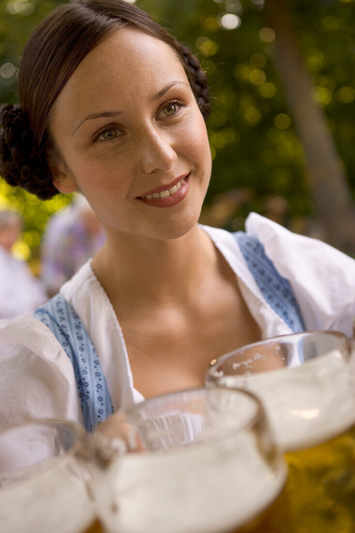 Young woman, waitress carrying beer glasses, beer steins, Lake Starnberg, Bavaria, Germany