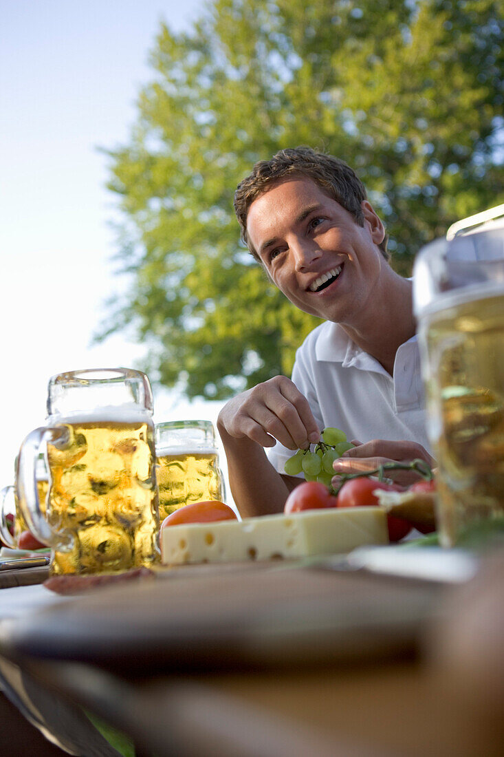Young man sitting at table with food and beer steins, Munich, Bavaria