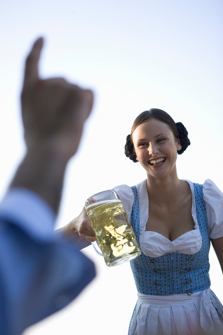 Waitress serving beer stein to guest in beer garden, Munich, Bavaria