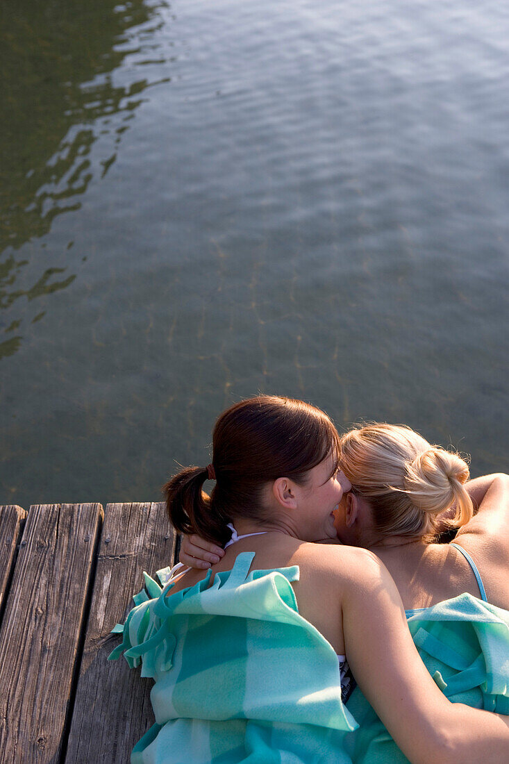 Two young women lying on boardwalk in blanket, Munich, Bavaria