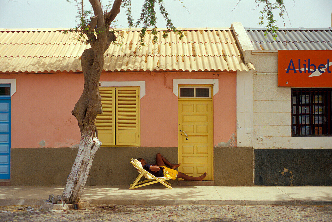 Teenager asleep in a deck chair, Street in Santa Maria, Santa Maria, Sal, Cape Verde Islands, Africa