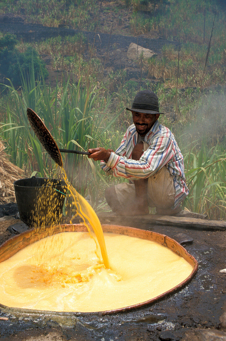 Man at huge cauldron filled with liquor of sugar cane, Paul, Santo Antao, Cape Verde, Africa