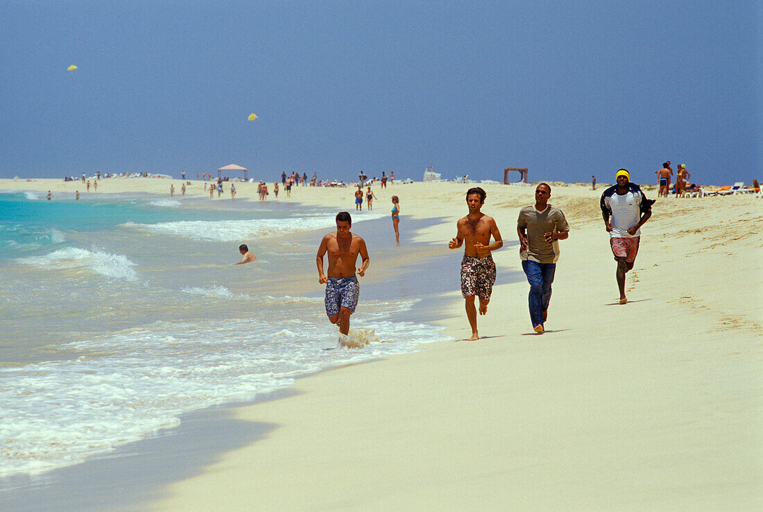 Junge Männer laufen am Strand entlang, Santa Maria, Sal, Kap Verde, Afrika