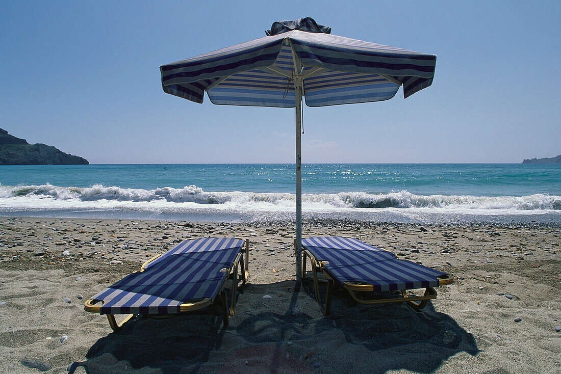 Zwei Sonnenliegen und ein Sonnenschirm, Am Strand von Plakias, Kreta, Griechenland