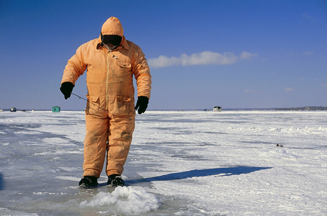 Ice Fishing, a man standing on frozen St. Lawrence River, Quebec, Canada
