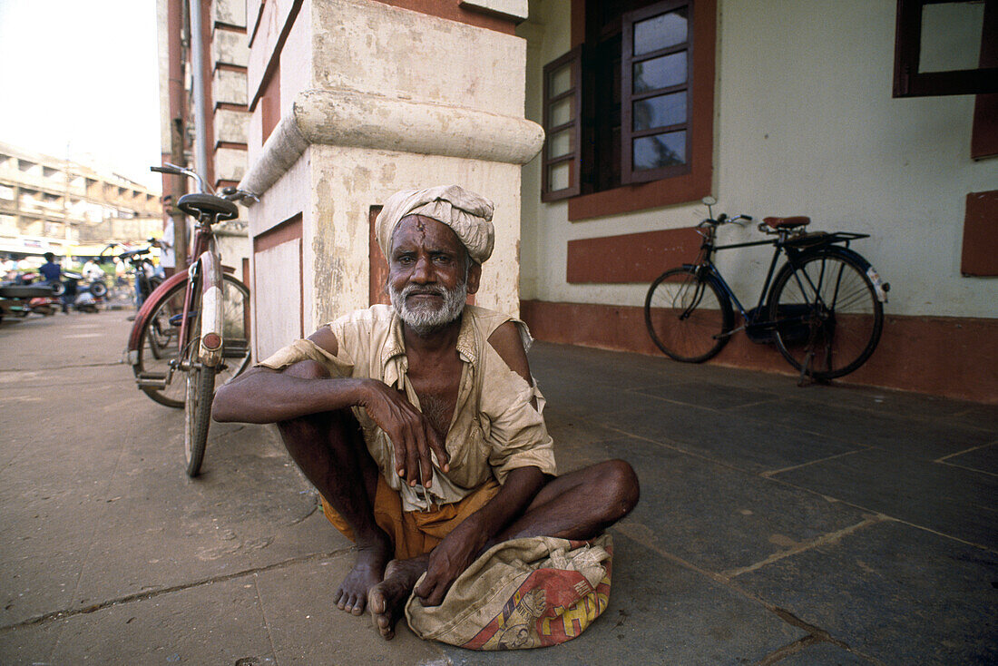 Bettler, ein älterer Mann sitzt auf dem Boden, Margao, Goa, Indien