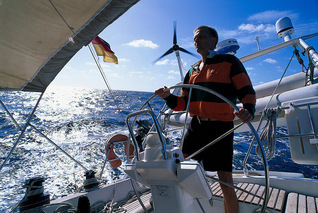 Mann am Steuerrad eines Segelboots im Sonnenlicht, St. Vincent, Grenadinen, Karibik, Amerika