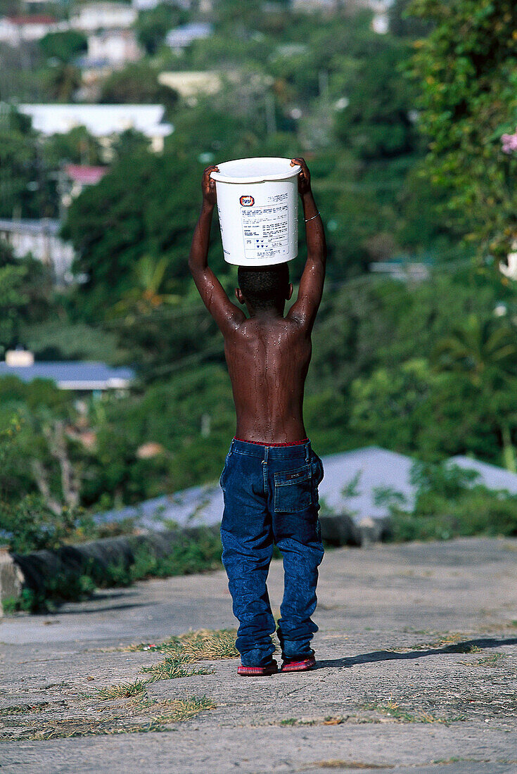 Junge traegt Trinkwasser, Port Elizabeth, Bequia St. Vincent, Grenadinen
