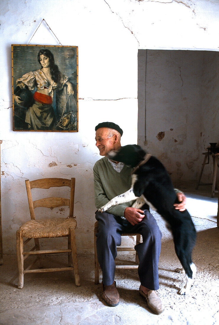 An old man and a dog in the farmworker's room of a finca, Son Brui, Majorca, Spain
