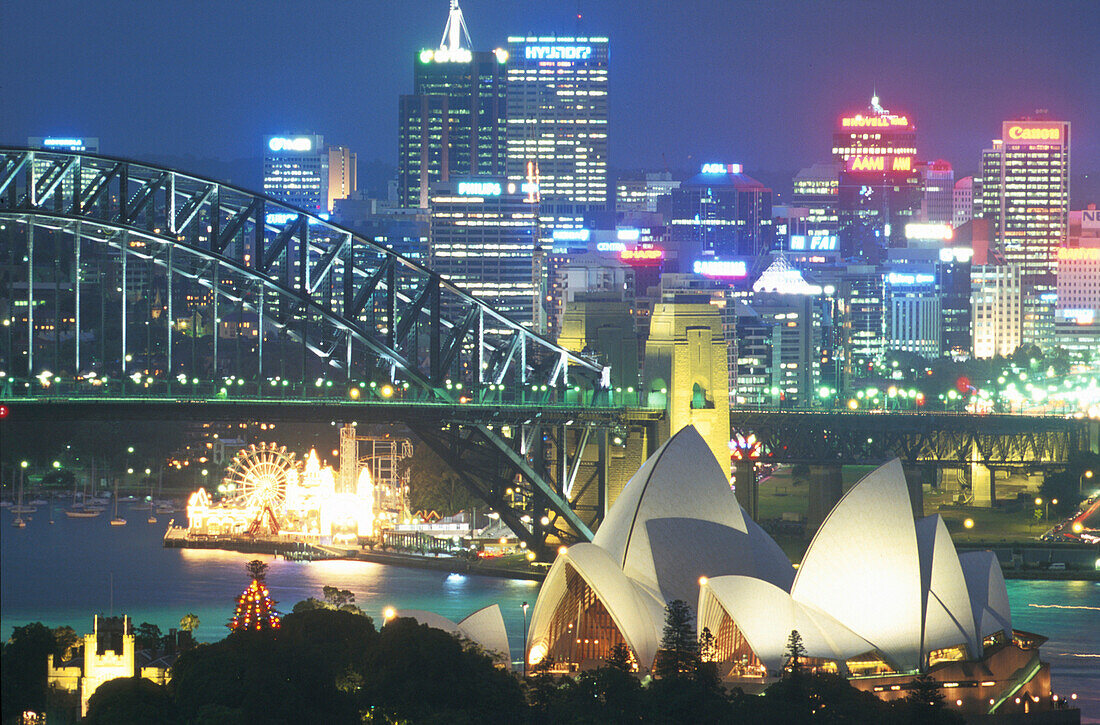 Opera House, Habour Bridge und Luna Park vor beleuchteten Hochhäusern, Sydney, New South Wales, Australien