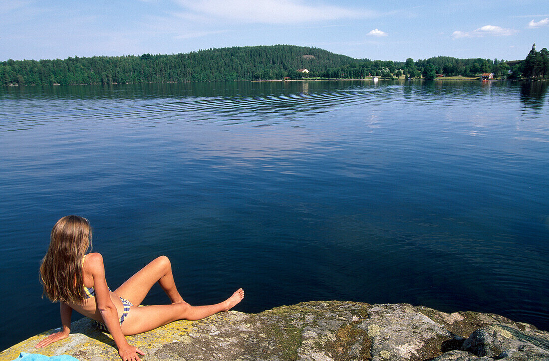 Woman sunbathing at lake Sommen, East Tranas, Oestergotland, Sweden