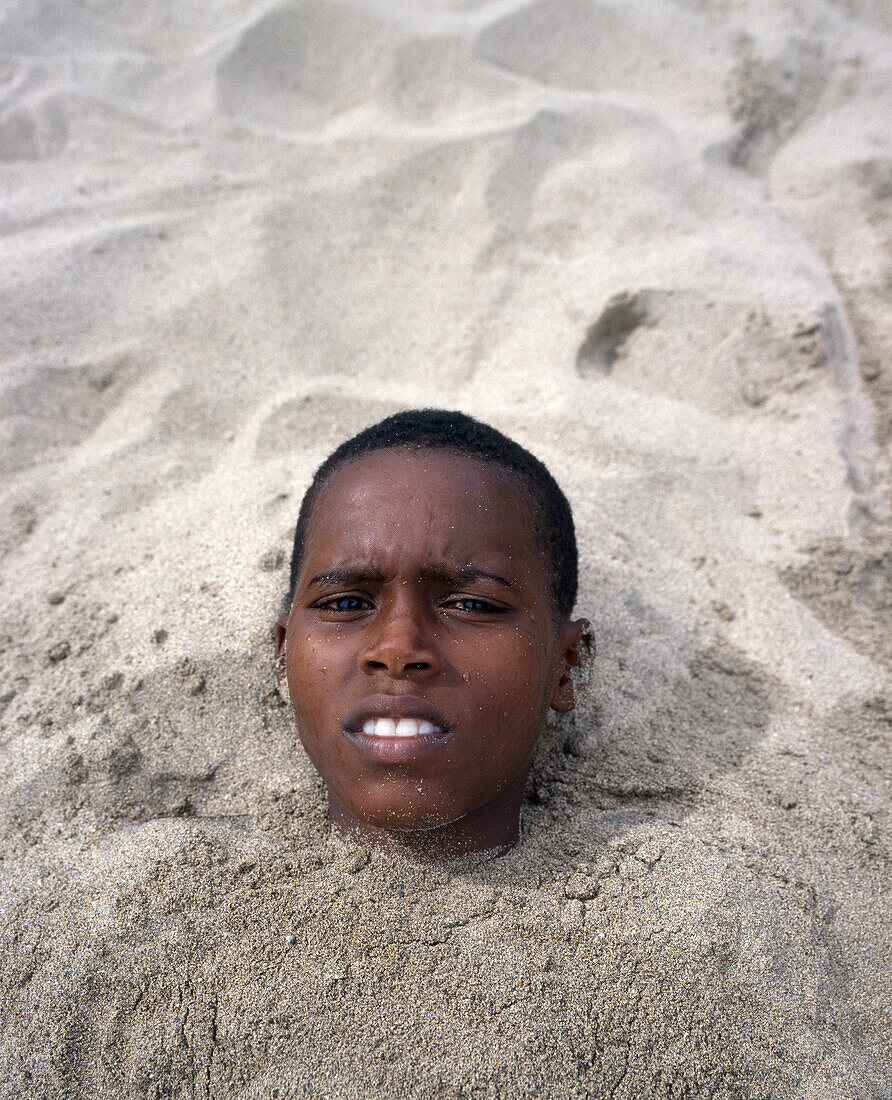 Einheimischer Junge vergraben im Sand, Portrait, Kapverden
