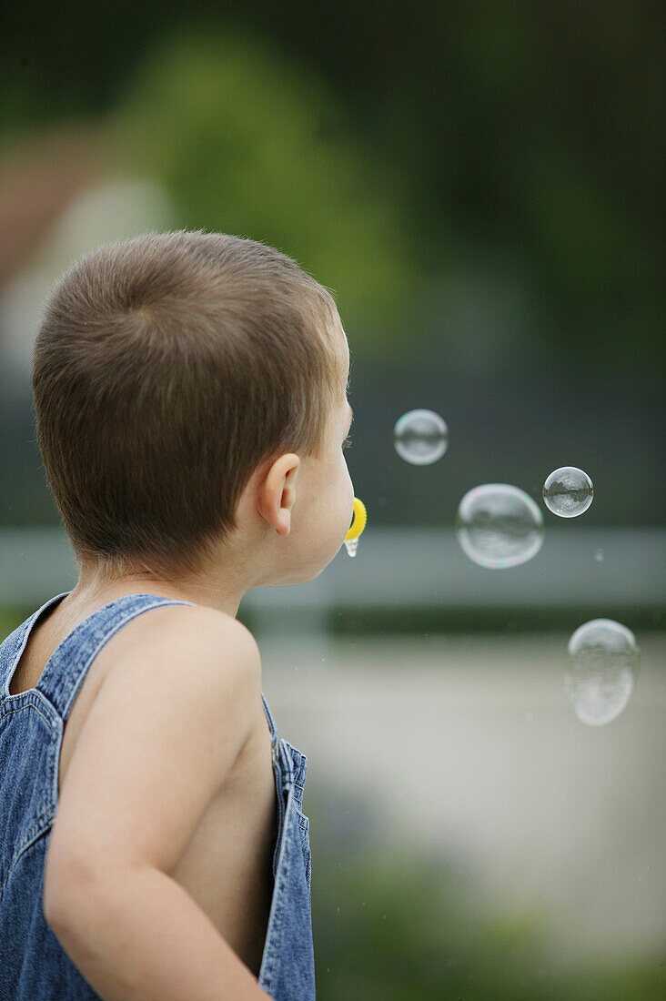 Boy making soap-bubbles, people