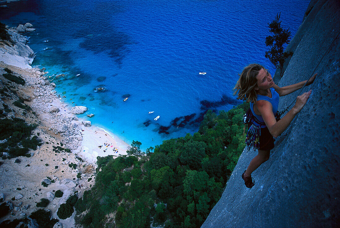 Female free climber scaling rock face, Cala Goloritze, Sardinia, Italy