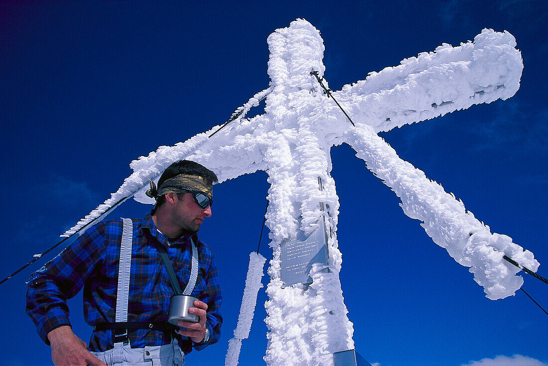 Bergsteiger am Gipfelkreuz des Hochmölbing im Winter, Totes Gebirge, Oberösterreich, Österreich