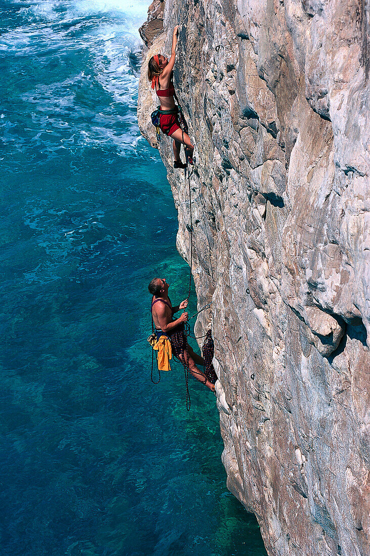 Couple freeclimbing up a rock face, Finale Ligure, Liguria, Italy