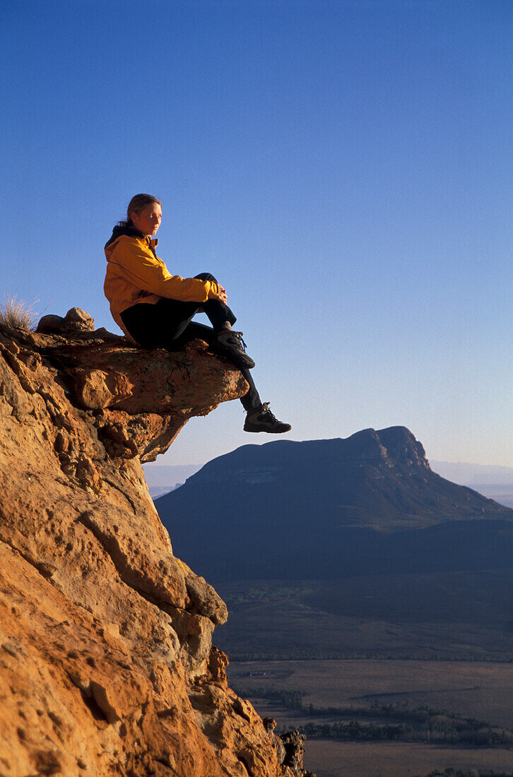 Frau mittleren Alters sitz auf einem Felsen, Harrismith, Südafrika