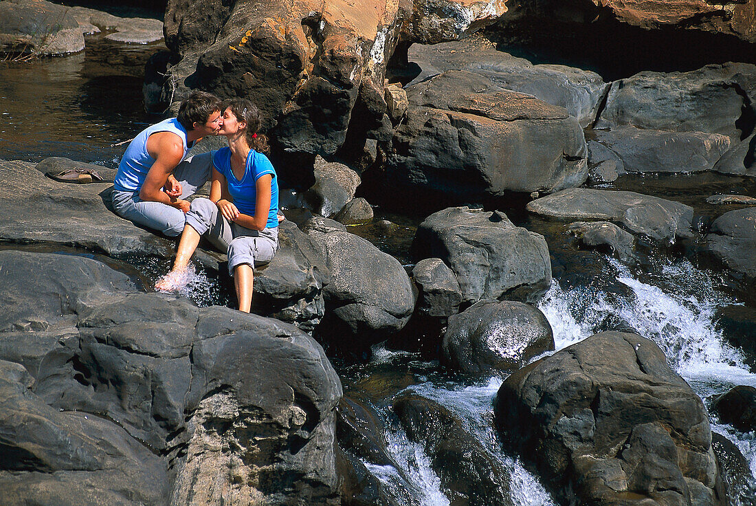 Couple kissing on rocks by a stream, Mpumalanga, South Africa