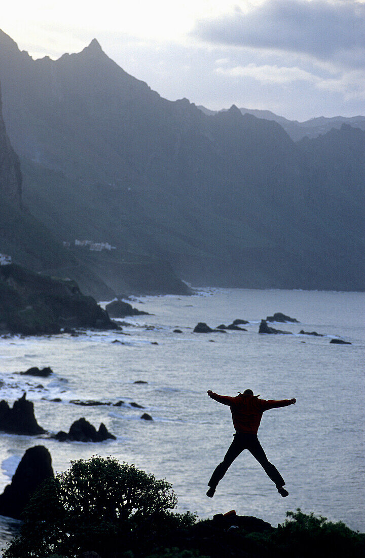 Mann macht einen Sprung in der Luft, Küste in der Nähe von Taganana, Anaga Gebirge, Teneriffa, Kanarische Inseln, Spanien
