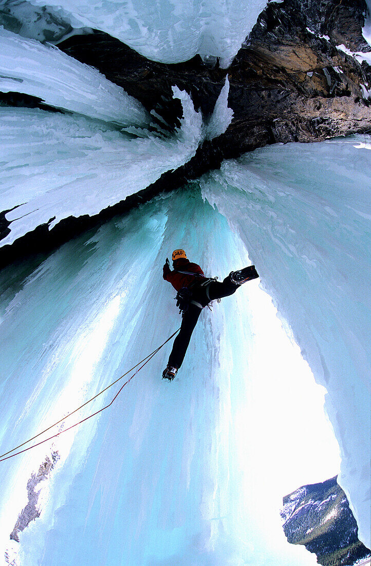 Mann klettert in eine Eishöhle, Golden Area, Banff Nationalpark, Kanada
