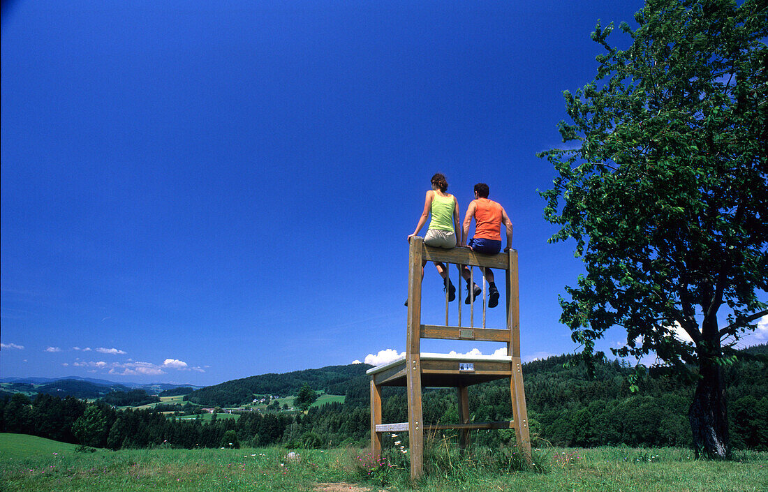 Paar sitzt auf einen Riesenstuhl, Bankerlsteig, Mühlviertel, Oberösterreich, Österreich