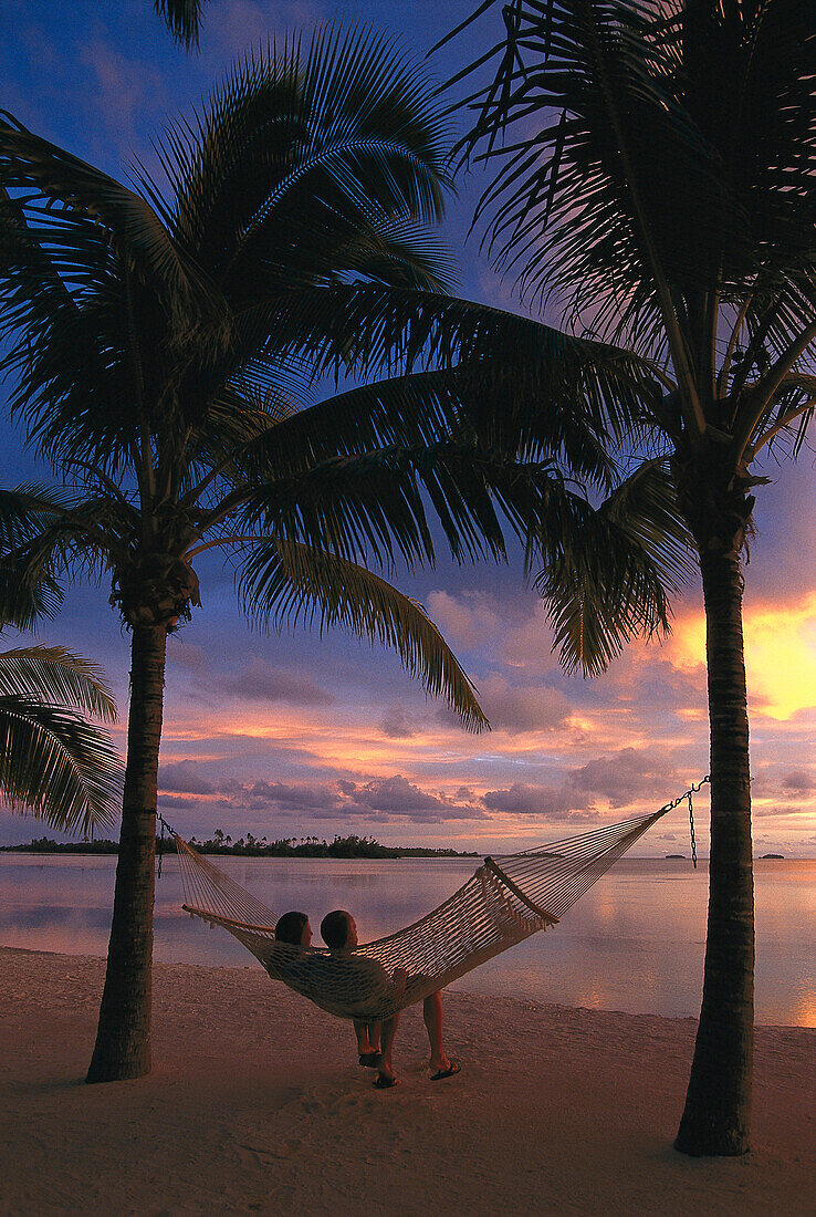 Couple relaxing in a hammock at sunset, Aitutaki Lagoon Resort, Cook Islands, South Pacific