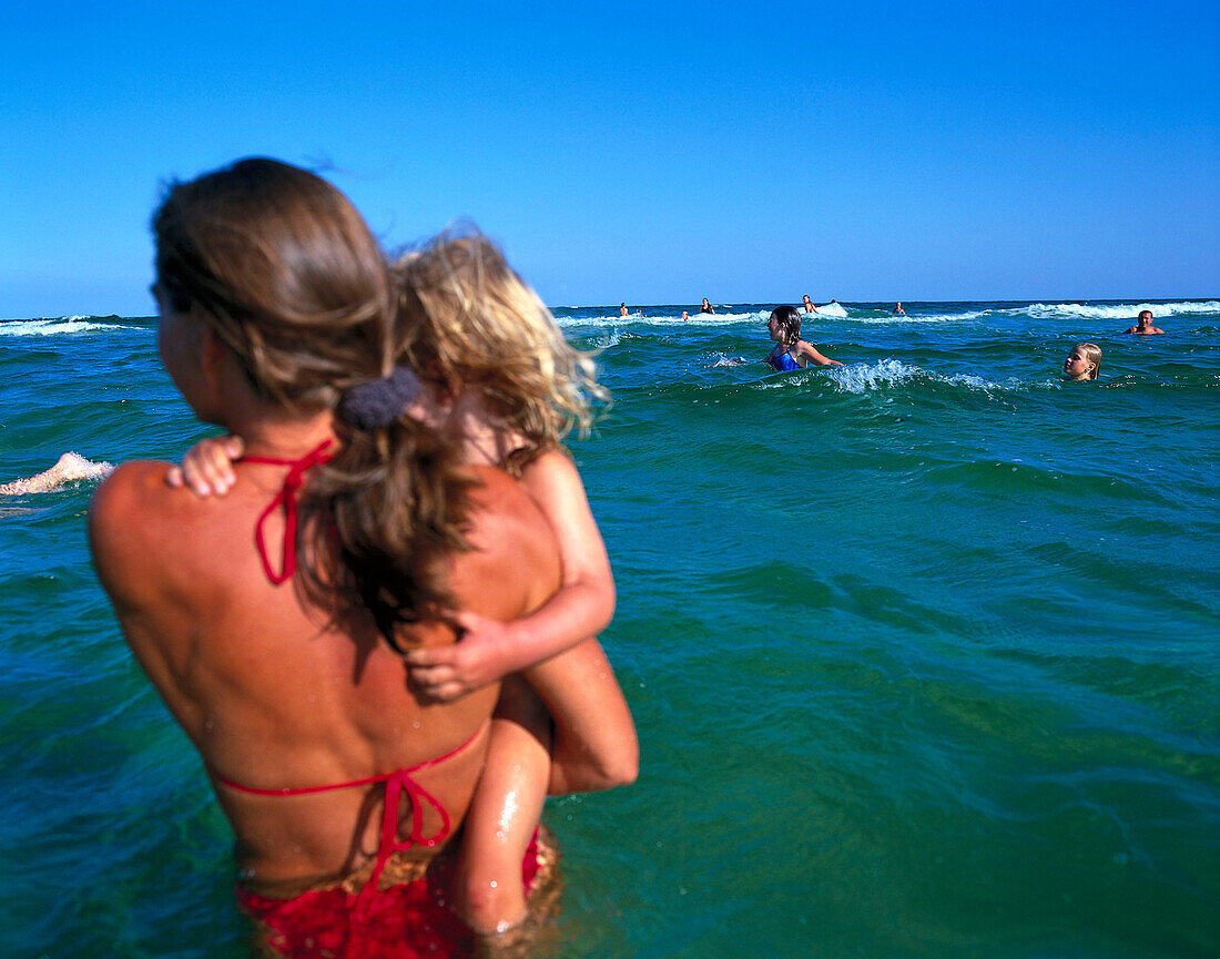 Woman standing in water, holding daughter on arms, Dueodde, Bornholm, Baltic Sea, Denmark