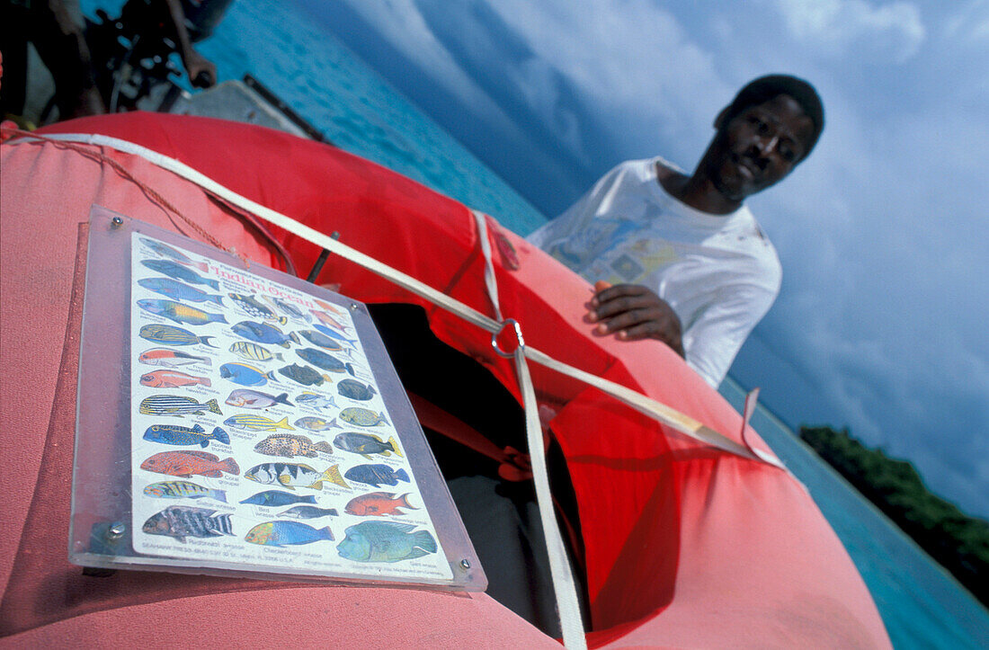Afrikanischer Mann mit Rettungsring und Informationstafel auf einem Boot, Chumbe Insel, Sansibar, Tansania, Afrika