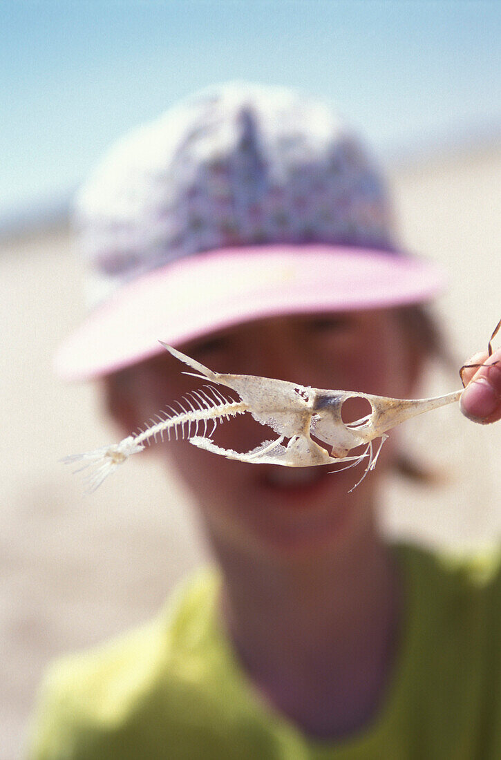 Girl holding skeleton of a fish, Parque Natural da Ria Formosa, Algarve, Portugal