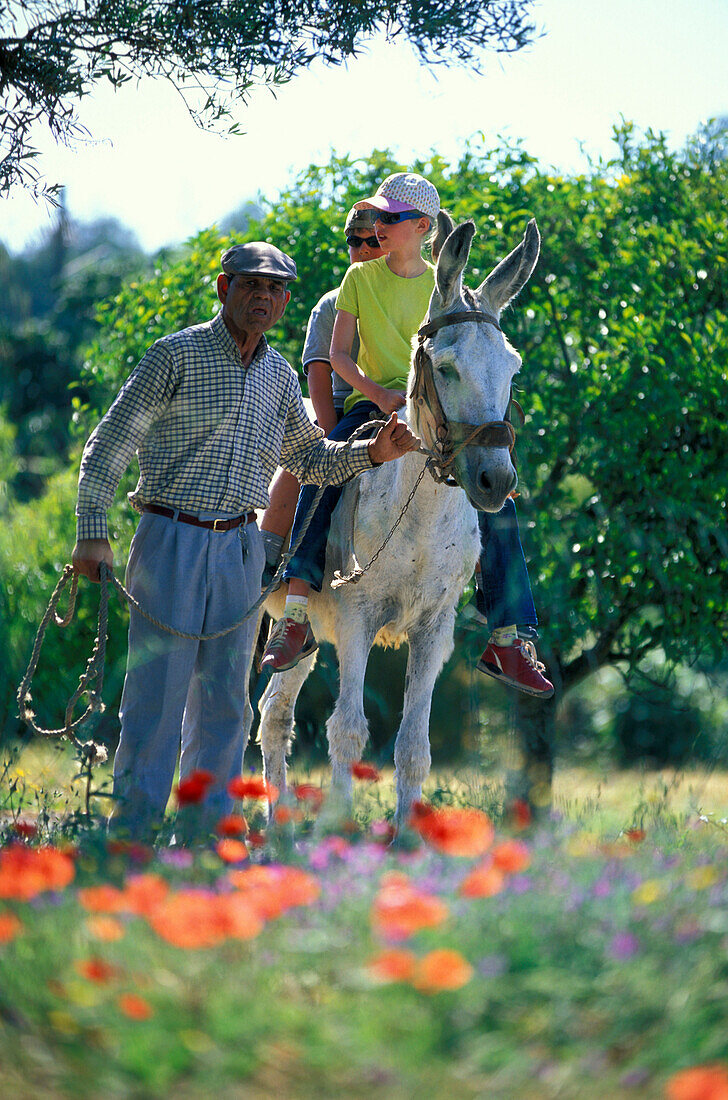 Two children riding a donkey, Quinta da Fonte do Bispo, Tavira, Algarve, Portugal, Europe