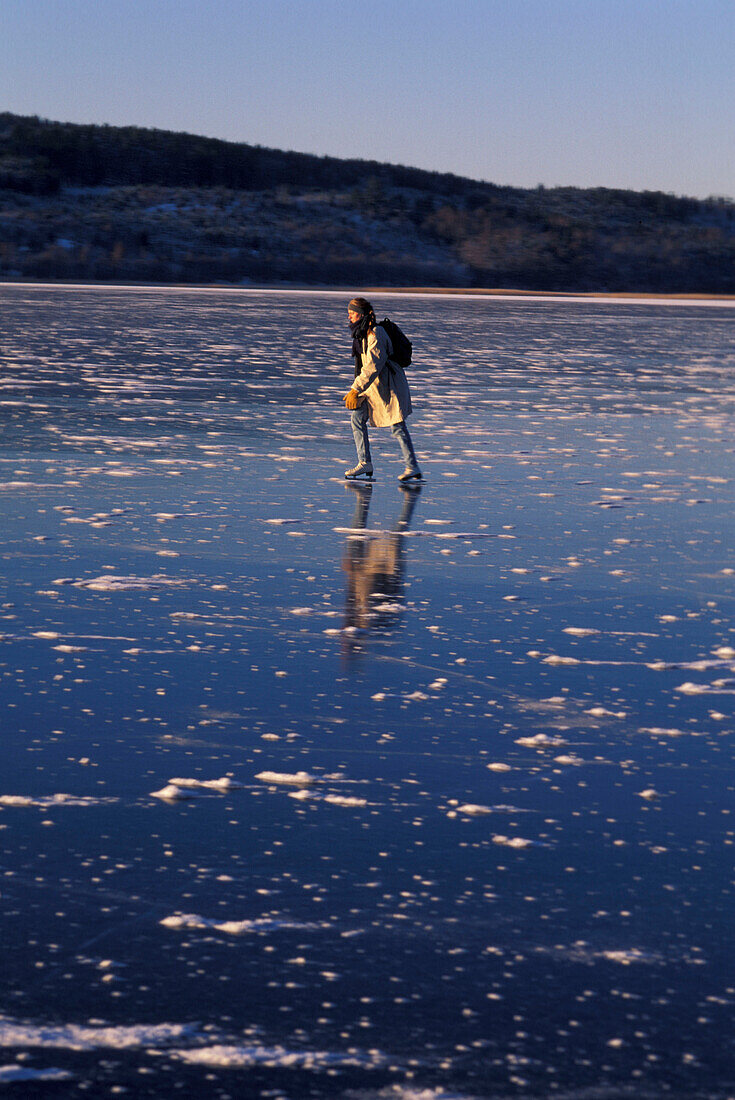 Woman skating on ice, lake in Vastergotland, Sweden