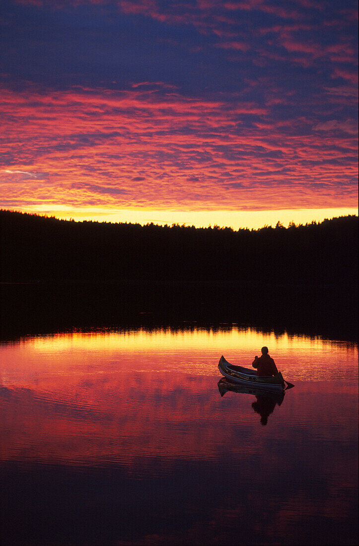 Kanutin paddelt auf See, Sonnenuntergang spiegelt sich, Västergötland, Schweden