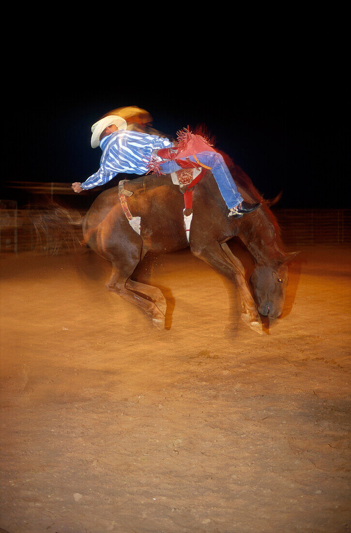 Cowboy auf Bronco beim Rodeo, Amateur-Rodeo, nachts in Lubbock, Texas