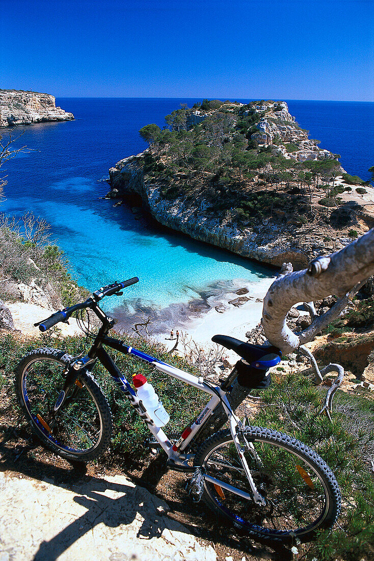 Mountainbike vor einer Bucht mit Strand unter blauem Himmel, Cala S´Amonia, Mallorca, Spanien, Europa