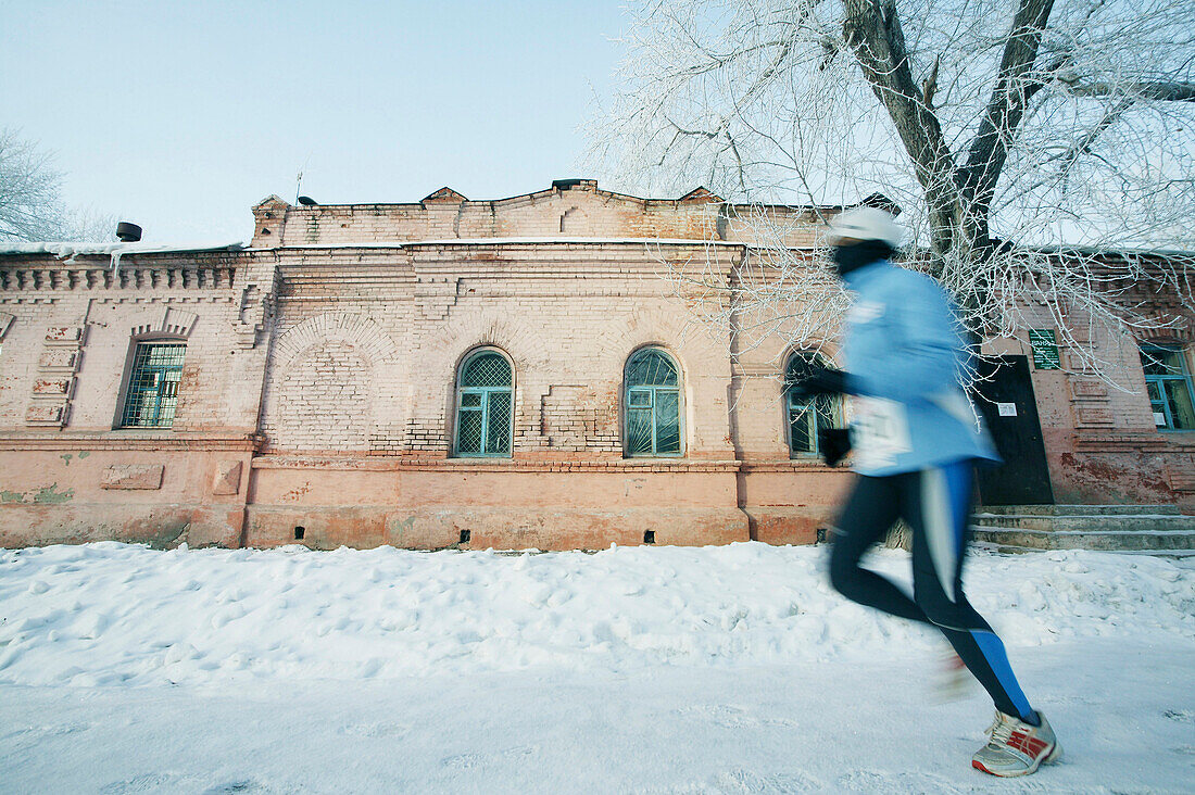 Läufer läuft über verschneite Strasse, Omsk, Siberien, Russland