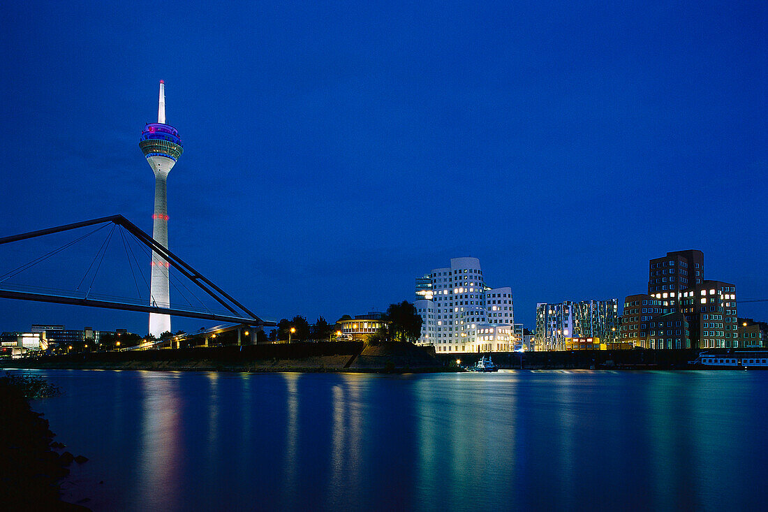 Illuminated buildings of the media harbour at night with Rheinturm and Neuer Zollhof, Duesseldorf, North Rhine Westfalia, Germany