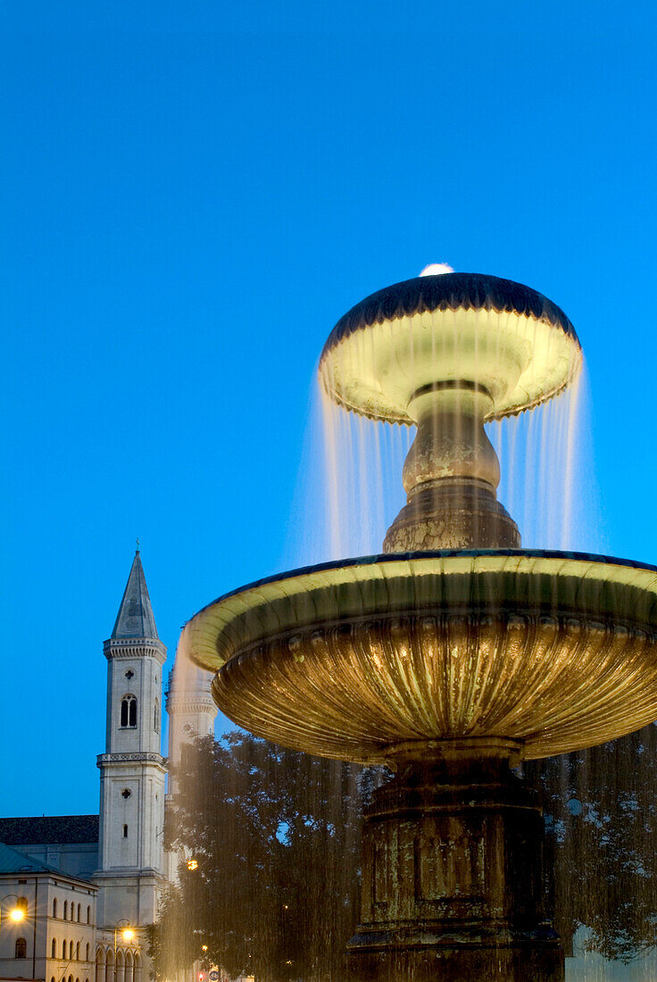 Illuminated fountain in front of Ludwigskirche and University, Ludwigstrasse, Munich, Bavaria, Germany