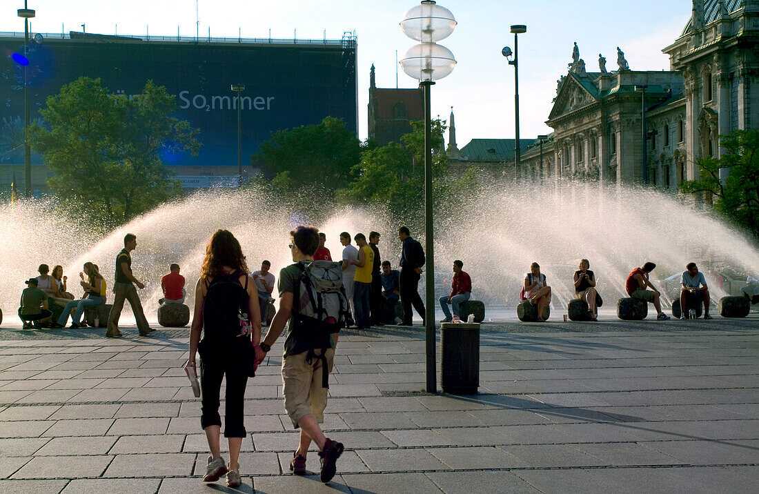 Brunnen am Stachus, Touitsts walking in front of Fountain at Stachus, Munich, Bavaria, Germany