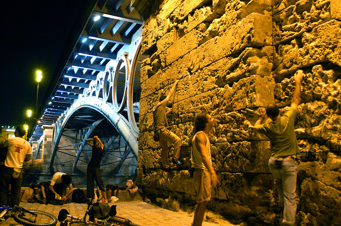 Menschen klettern an einer Mauer hoch, Puente de Triana, Sevilla, Andalusien, Spanien