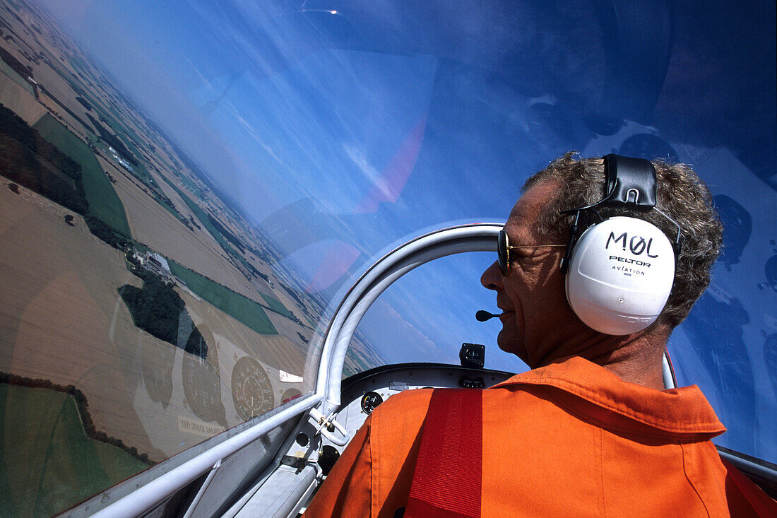 Pilot mit Kopfhörer im Flugzeug, Luftaufnahme über Lolland, Dänemark