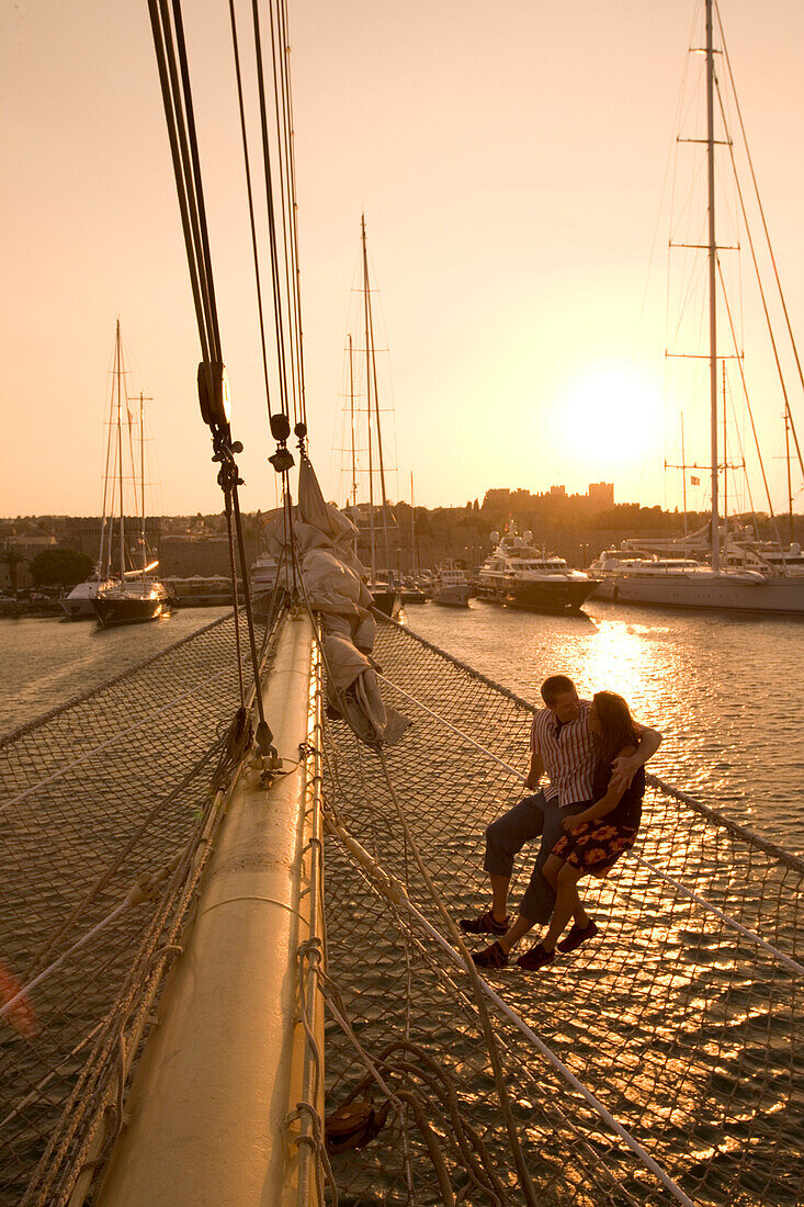Paar sitz im Netzt, Bugsprietnetz, Star Flyer, Sonnenuntergang über Rhodos Hafen, Rhodos, Dodekanes, Griechenland