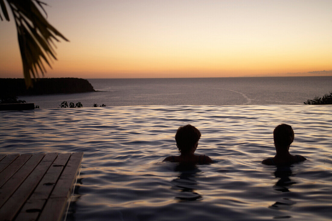 Menschen im Pool des Hotel Restaurant Le Rayon Vert im Licht der Abendsonne, Deshaies, Basse-Terre, Guadeloupe, Karibik, Amerika