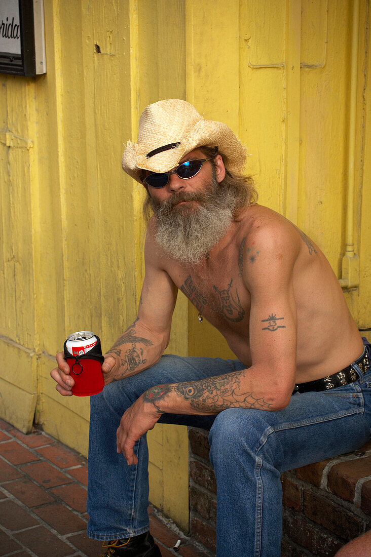 Ein mann sizt vor dem Haus und trinkt Bier, Key West, Florida Keys, Florida, USA