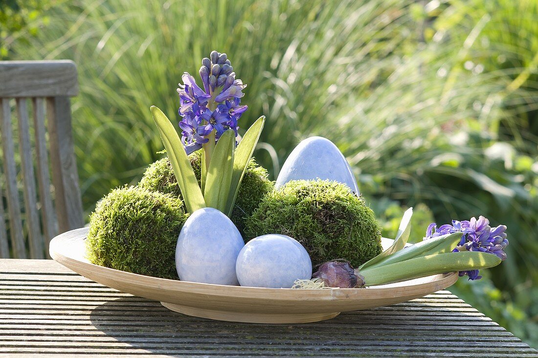 Osternest auf einem Gartentisch mit Blumen und Moos